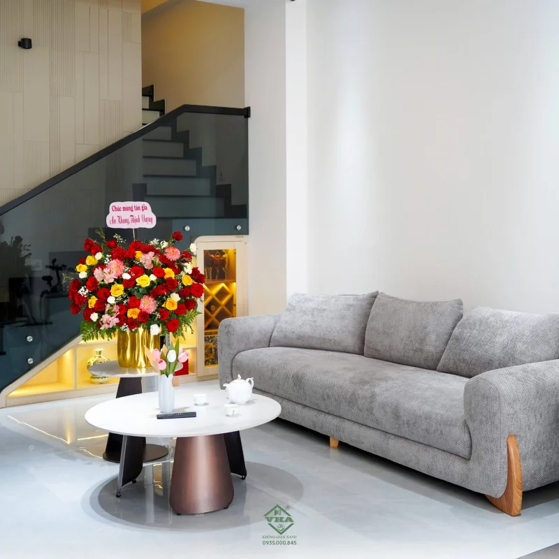Không gian phòng khách nhà phố hiện đại sử dụng nội thất tối giản, kết nối liền mạch với cầu thang và khu bếp.