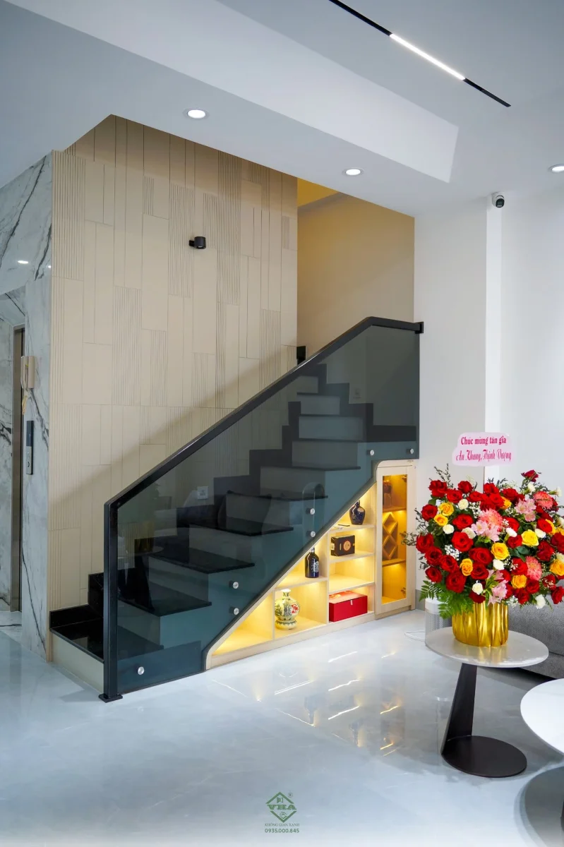 Thiết kế cầu thang kính cường lực kết hợp tủ trang trí dưới gầm cầu thang trong nhà phố hiện đại.